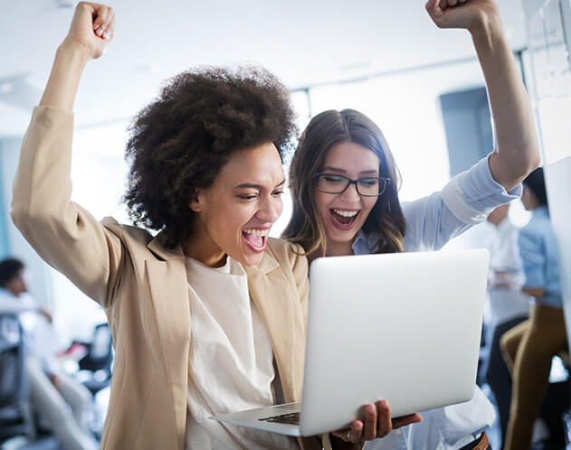Two colleagues celebrating while looking at a laptop